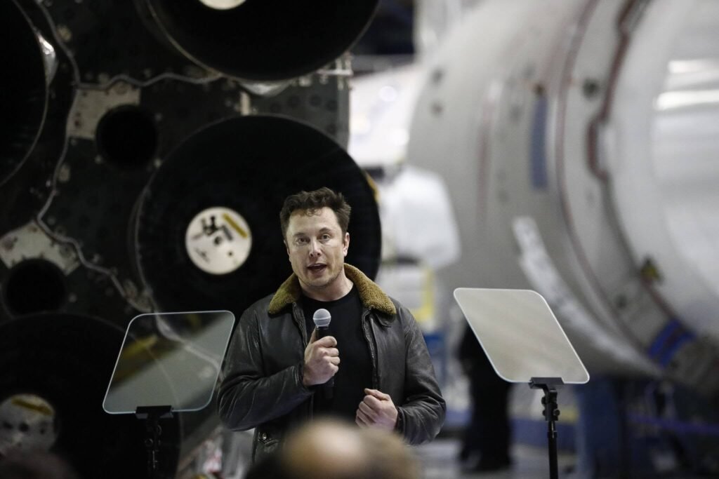 Elon Musk standing in front of a SpaceX rocket representing the world's first trillionaire and the potential $75 billion SpaceX IPO.